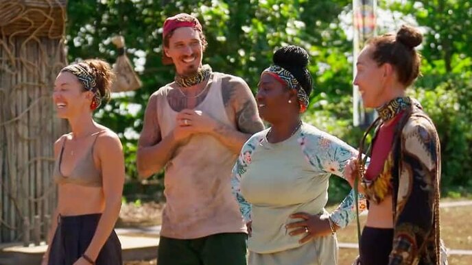 Four vibrant reality TV cast members laughing and chatting outdoors in tropical setting