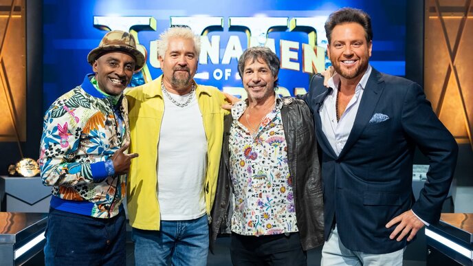 A group of four men smiling and posing together on the set of a game show, with a "TNA" logo in the background, celebrating their participation in the Tournament of Champions 7 episode 4 recap.